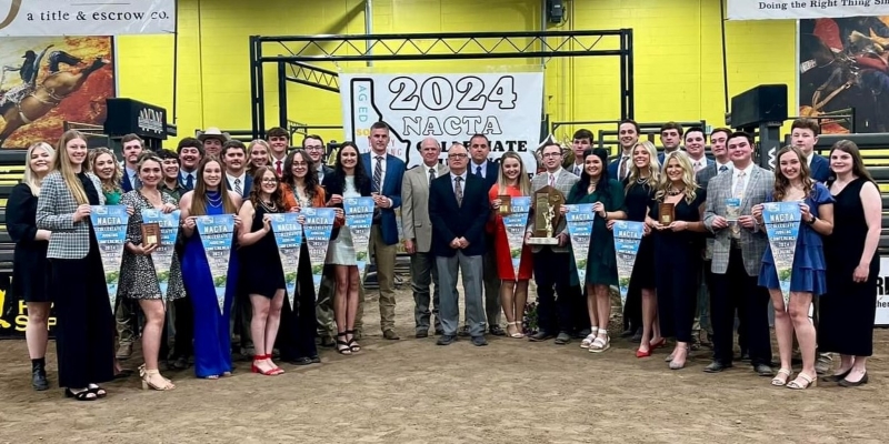 30 students and 4 coaches standing in ag arena with awards