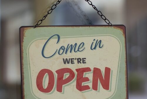 hanging metal sign that says Come in we're open