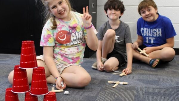 3 youths sitting on floor and smiling at camera