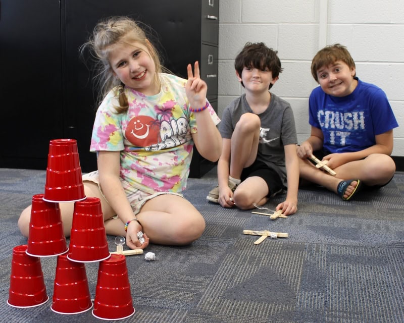 3 youths sitting on floor and smiling at camera