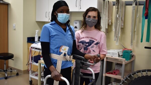 two physical therapist assistant students with a walker in a classroom