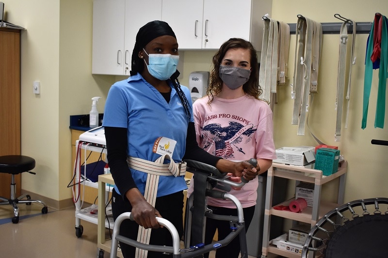 two physical therapist assistant students with a walker in a classroom