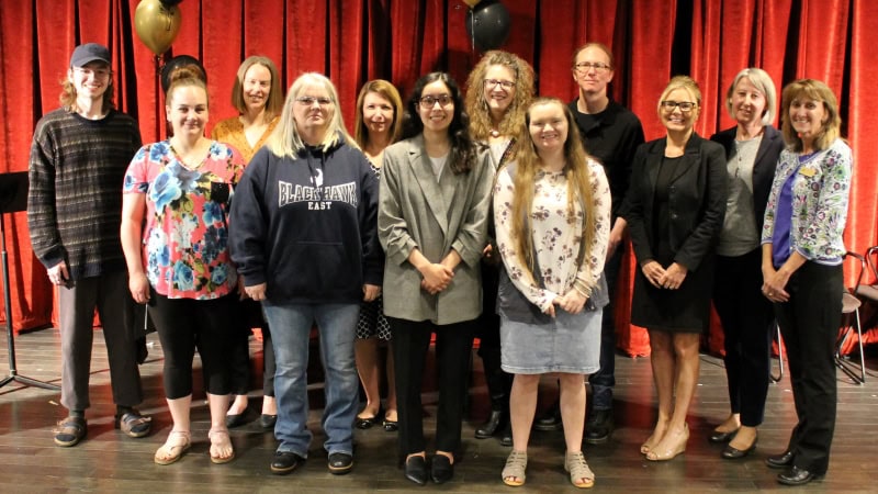 12 people standing & smiling at camera