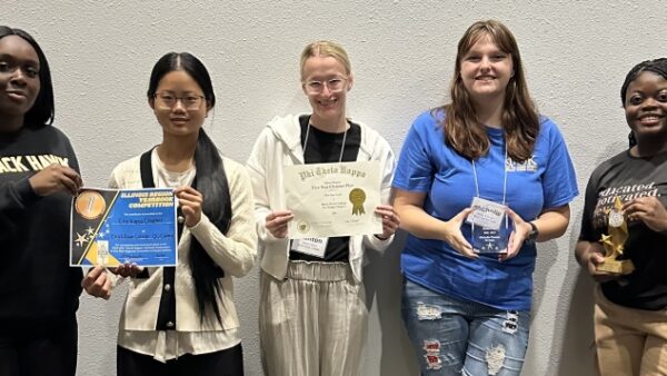 5 smiling students standing together holding awards and certificates