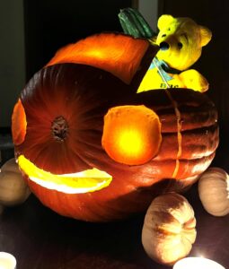 smiling carved pumpkin with wheels & teddy bear