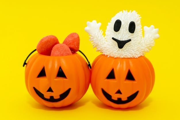 two small plastic pumpkins with a ghost inside one