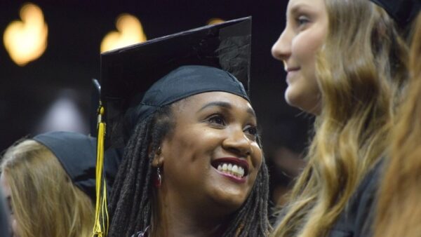 woman wearing black graduation cap smiles during the ceremony