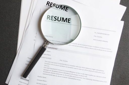 magnifying glass on top of resumes