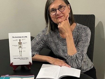 woman sitting at table covered with books