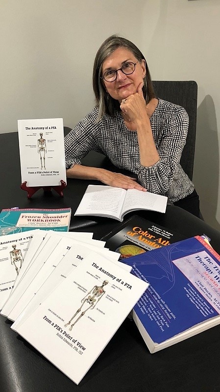 woman sitting at table covered with books