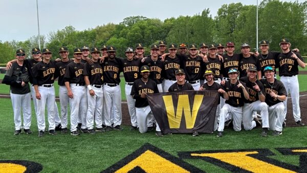 29 BHC baseball players on field smiling at camera with W banner