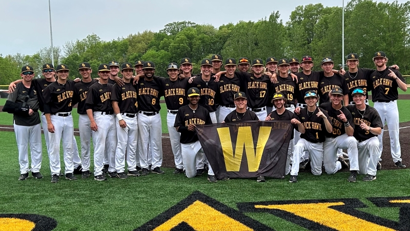 29 BHC baseball players on field smiling at camera with W banner