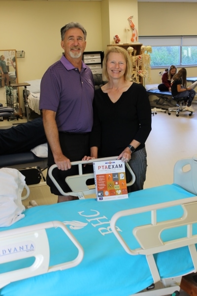 Steve & Leslie Shuman standing by new hospital bed in PTA classroom