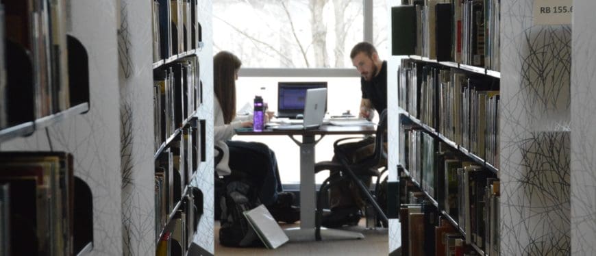 Two students studying at a table in the library