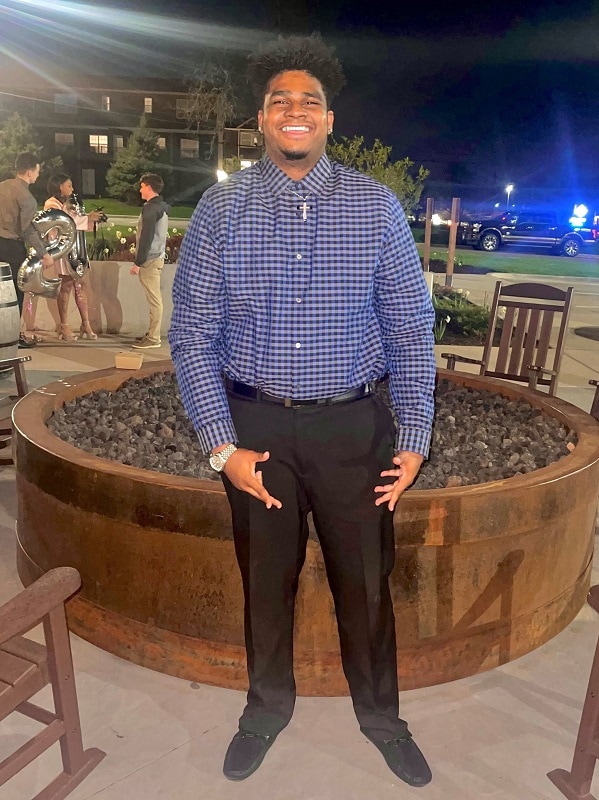 smiling male student standing on a patio at night