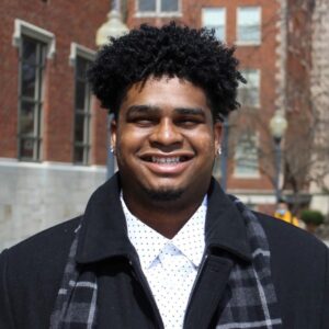 smiling male student with brick buildings in the background