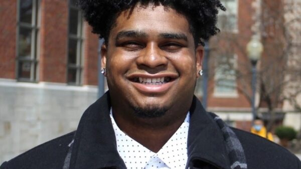 smiling male student with brick buildings in the background