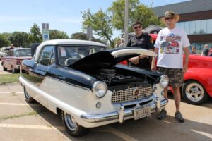 two people standing next to 1961 Metropolitan car