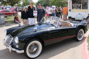 Three people standing next to 1960 MG car with 