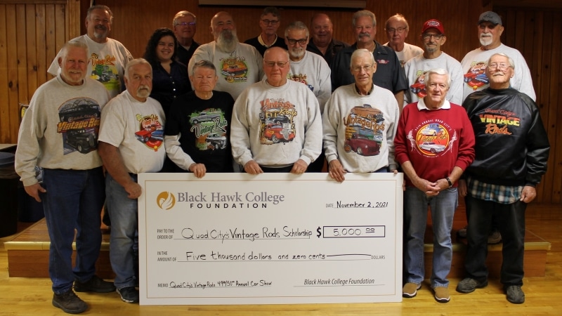 18 people standing with an oversized check