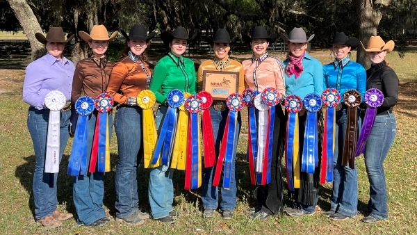 9 members of Western riding team standing with ribbons and plaque